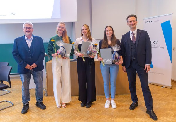 Gruppe dreier Studentinnen zwischen zwei Professoren in Hörsaal