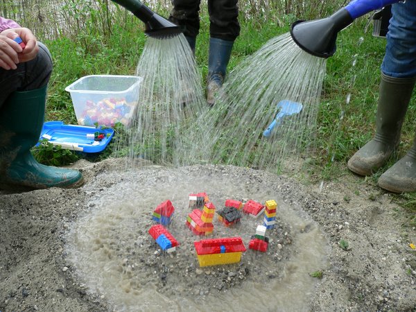 DWA RegenwasserTage 2026 mehrere Personen gießen auf Spielfiguren in einem Sanskasten