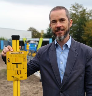Prof. Huhn Wasserstoff ein Mann steht nehem einem Gasschild mit der Aufschrift Wasserstoff