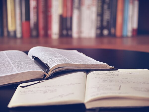 Ein Buch und ein Notizheft liegen versetzt aufeinander