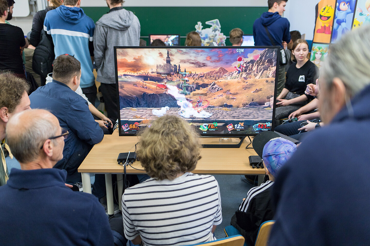 Lange Nacht der Computerspiele Mehrere Menschen sitzen um einen Monitor herum, auf dem ein Computerspiel läuft