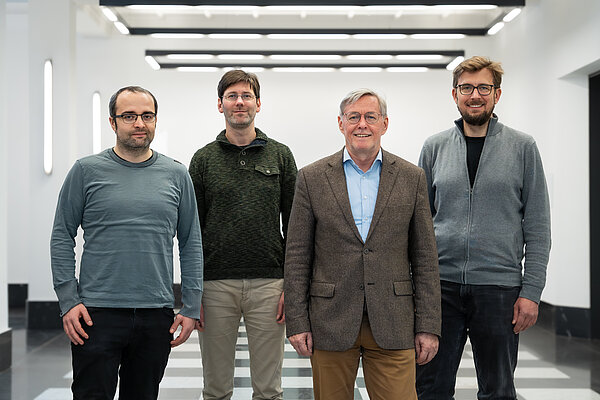 Forscher des Instituts für Betonbau Vier Männer stehen in einem Raum und schauen zur Kamera