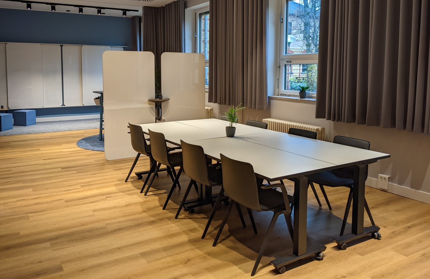 Schöner Meetingraum mit mehreren Whiteboards und einem großen Tisch mit 8 Stühlen.