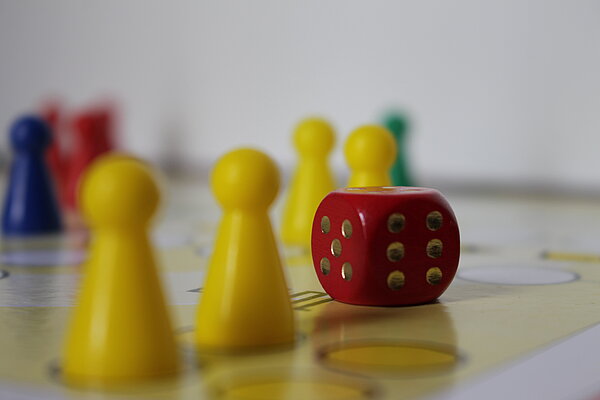 "Spielen - eine ernste Sache" Verschiedenfarbige Spielfiguren auf einem Spielbrett