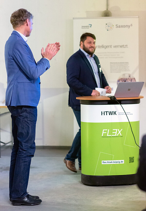 Dr. Hans-Martin Dörfler steht am Rednerpult und Prof. Alexander Stahr applaudiert
