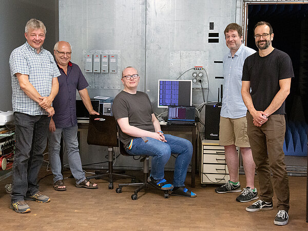 Messaufbau 5 Männer stehen vor der Absorberkammer und vor Computern