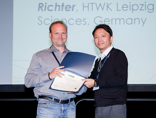 Best Paper Award für Hendrik Richter (Foto: World Congress on Computional Intelligence 2016) Prof. Hendrik Richter erhält von Konferenzleiter Prof. Yew-Soon Ong die Urkunde für seinen Konferenzbeitrag.