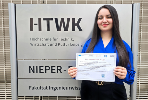 Taktak eine Frau steht vor dem Schild des Nieper-Baus der HTWK Leipzig und hält einen Zettel in der Hand