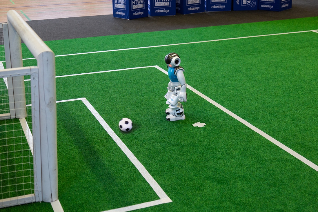 Auf dem Weg zum Tor – Nao-Roboter des HTWK-Teams. (Foto: Maximilian Johnson/HTWK Leipzig) humanoider Roboter kickt Fußball ins Tor
